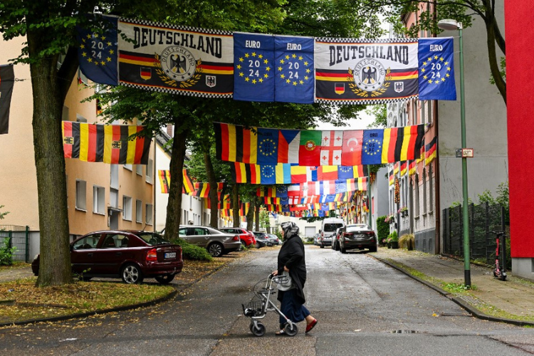 woman walks in front of flags of Germany and other european countries displayed by German football fan Achim Klimmeck in Rullichstrasse in Essen